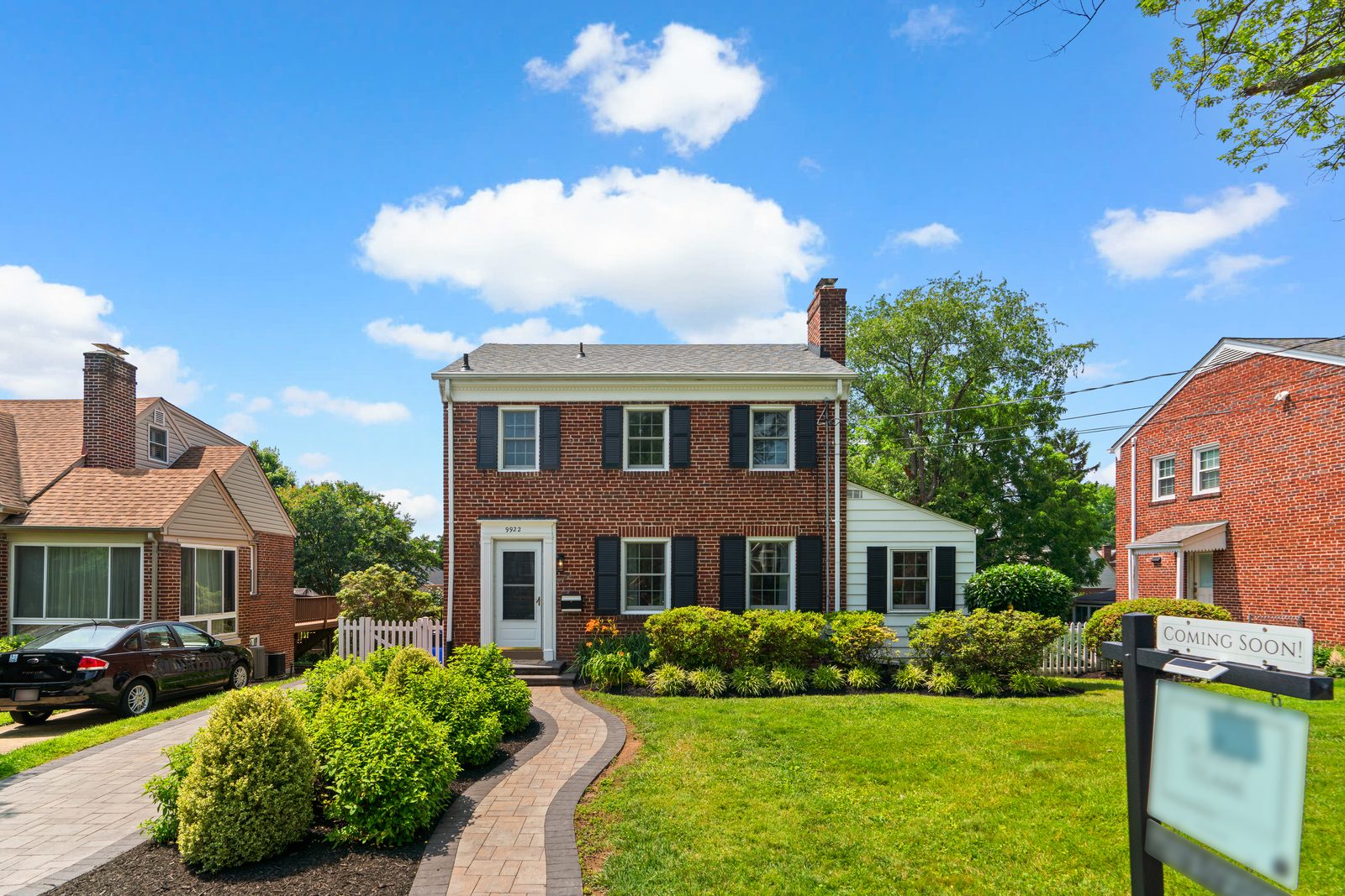 Brick colonial with black shutters and a coming soon sign
